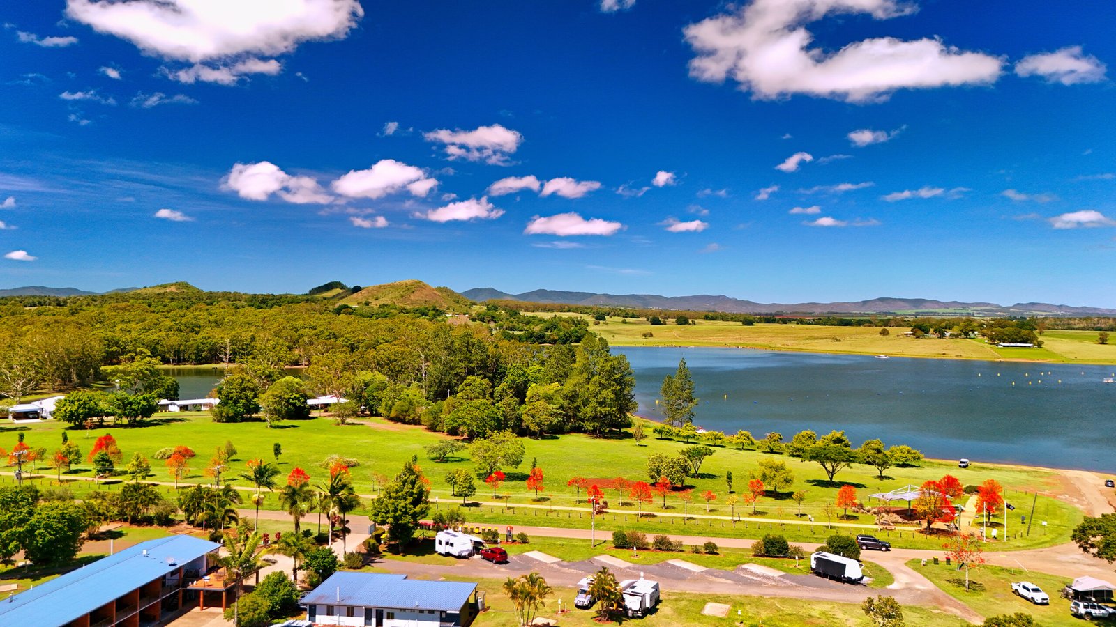 A breathtaking drone shot of the Tinaroo boat ramp and caravan park, showcasing the serene waters of Lake Tinaroo and the vibrant surrounding greenery.